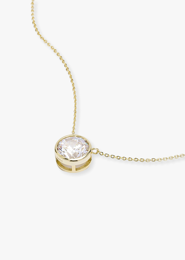 Gold necklace with a round simulated diamond pendant on a white background