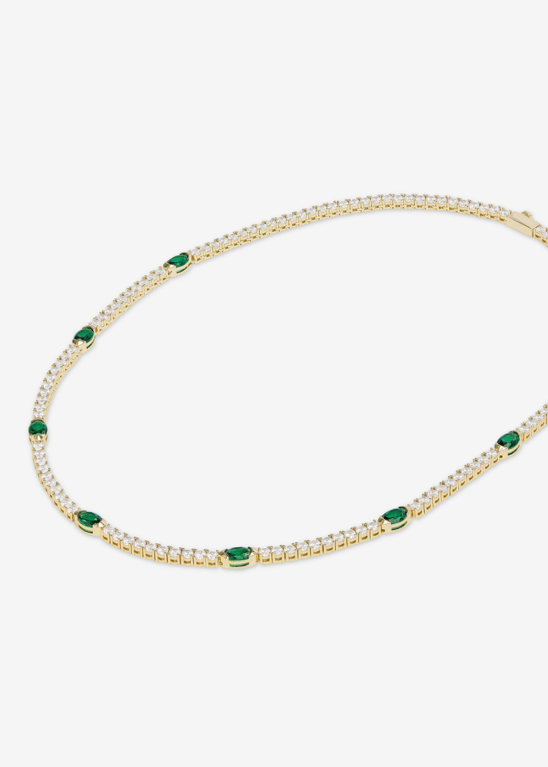 A gold framed simulated diamond and emerald tennis necklace on a white background
