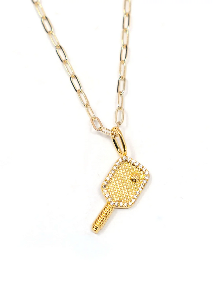 A gold pickleball charm on a gold chain necklace on a white background