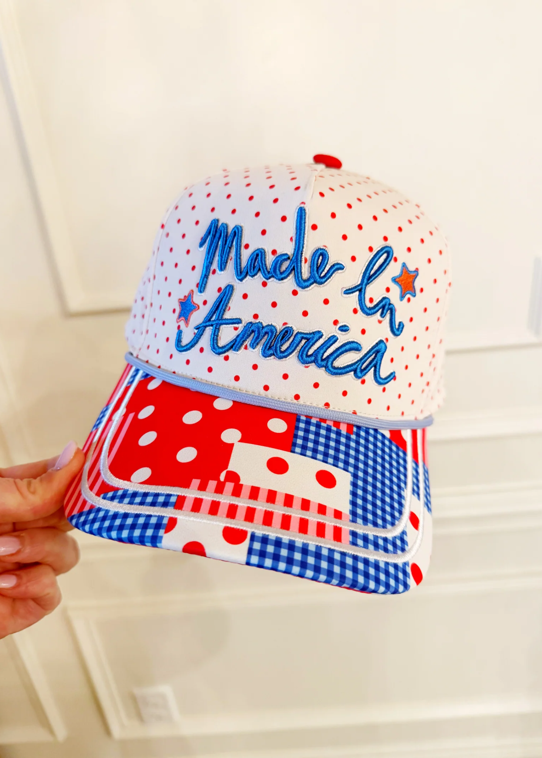 Hand holding a patterned trucker hat with a "Made In America" graphic