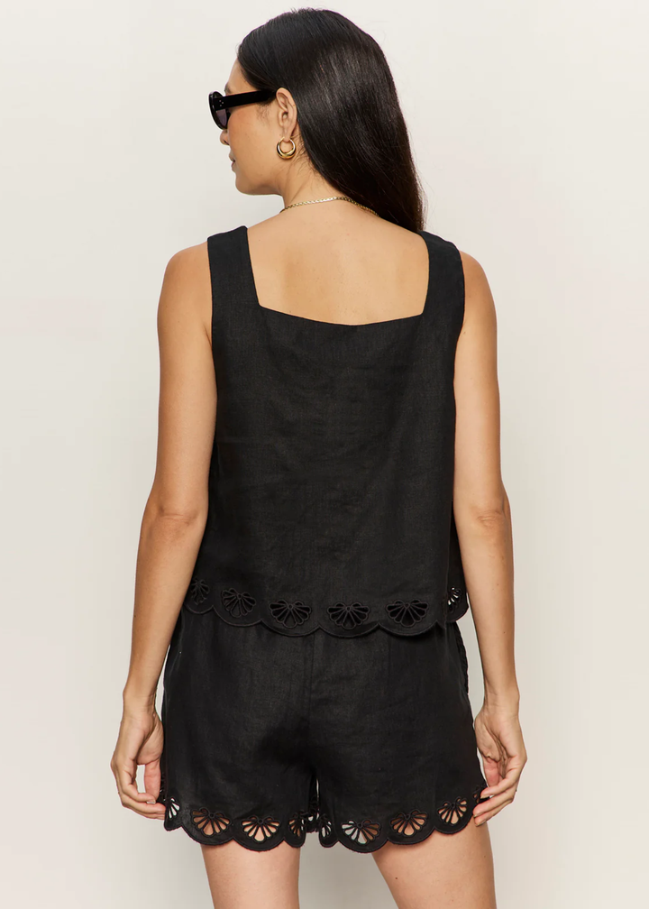Woman turned around wearing a black tank with an eyelet hem and matching shorts