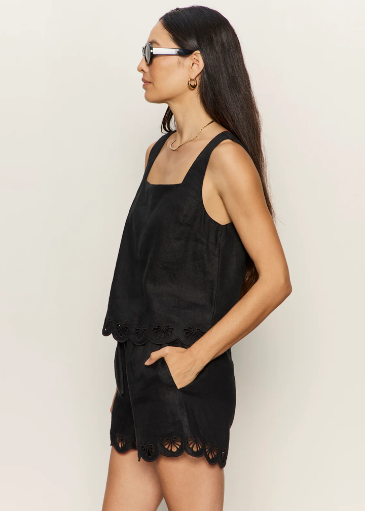 Woman turned to the side wearing a black tank with an eyelet hem and matching shorts