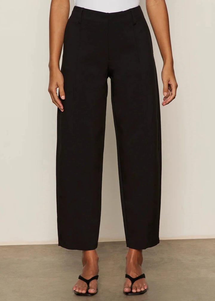 Person wearing black wide leg barrel pants with white top and black flip flops