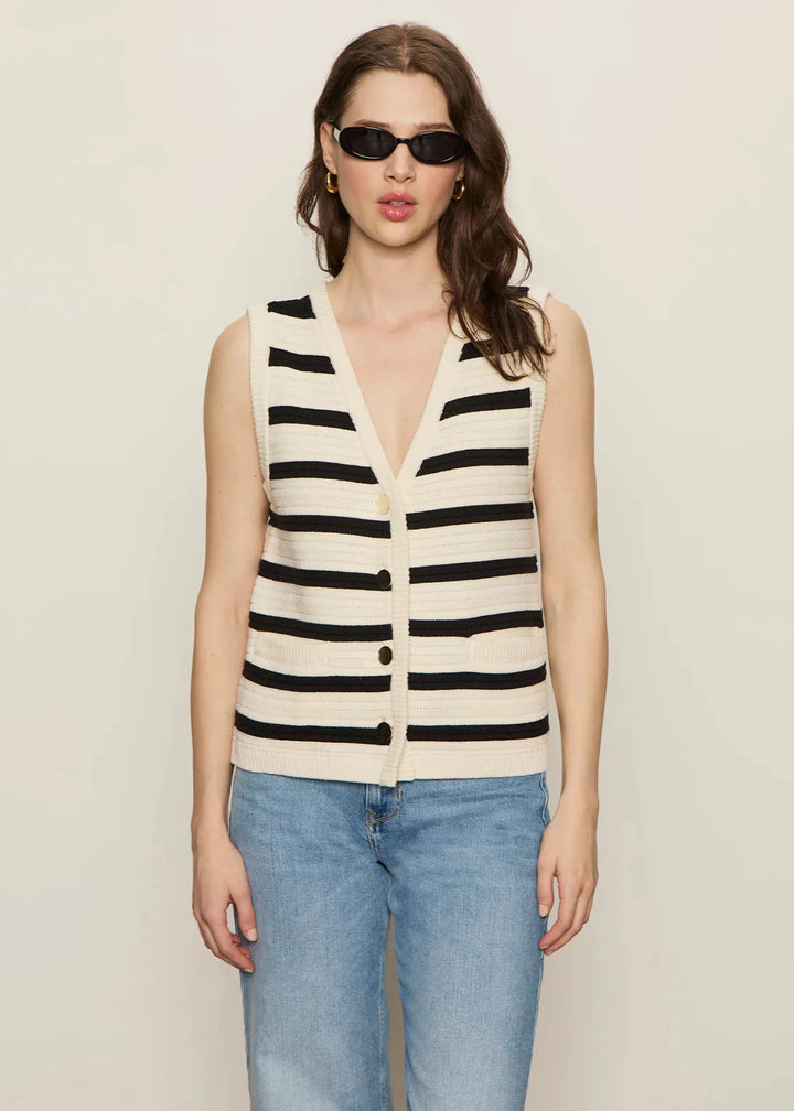 woman wearing cream and black textured knit sweater vest with coordinating buttons and front pockets