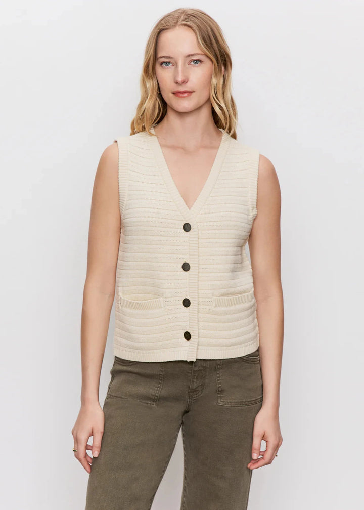 woman wearing cream textured knit sweater vest with black buttons and front pockets