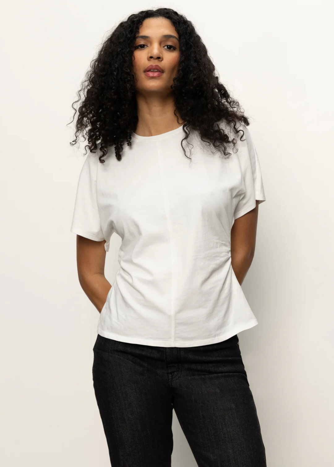 Woman wearing a white t-shirt with black pants in front of a white background