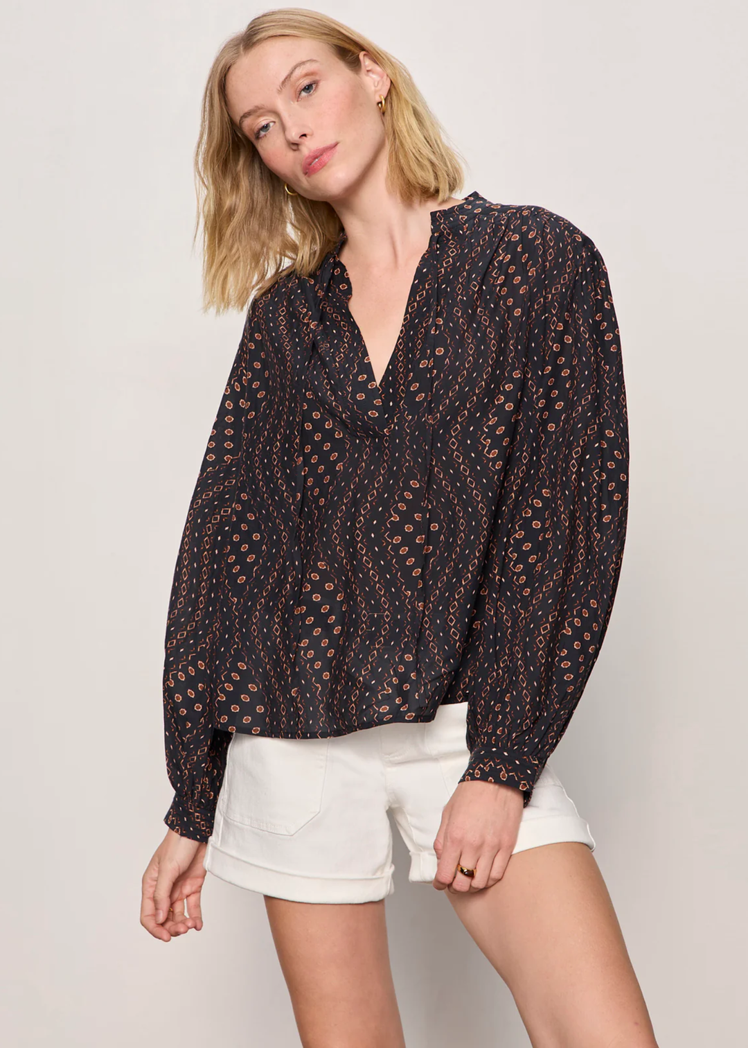 Woman wearing a black and brown patterned blouse with white shorts