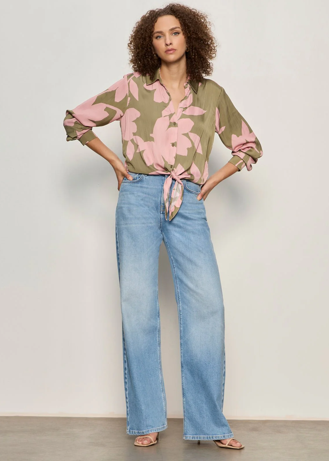 Woman wearing a green and pink floral button down tie front shirt with jeans