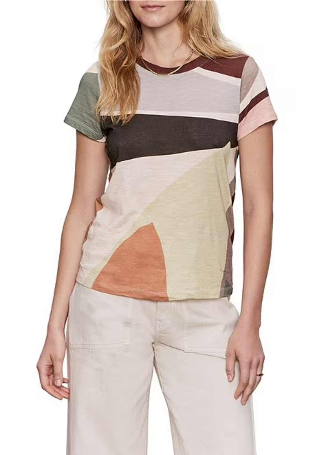 Woman wearing a multi color t-shirt and white pants in front of a white background
