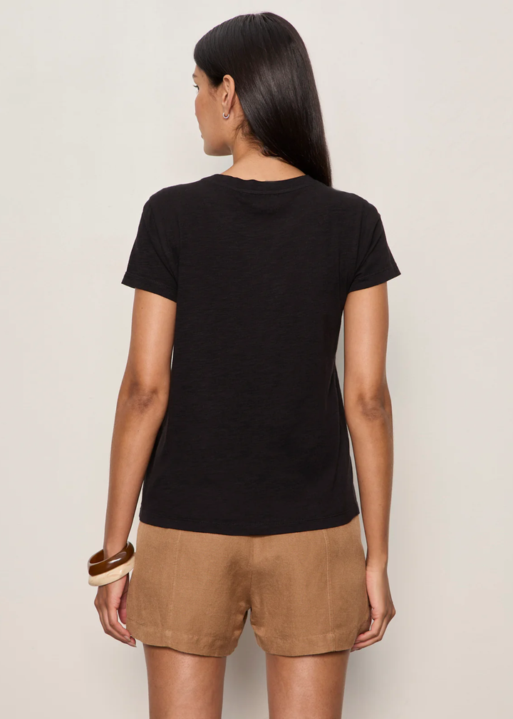 Woman turned around wearing a black t-shirt with brown shorts