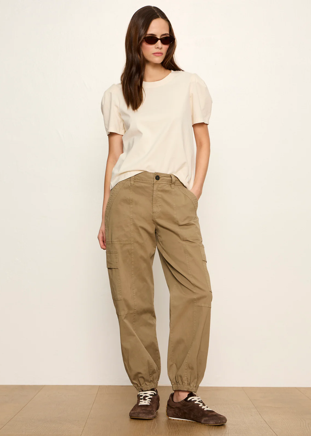 Woman wearing a cream top with tan pants and sunglasses
