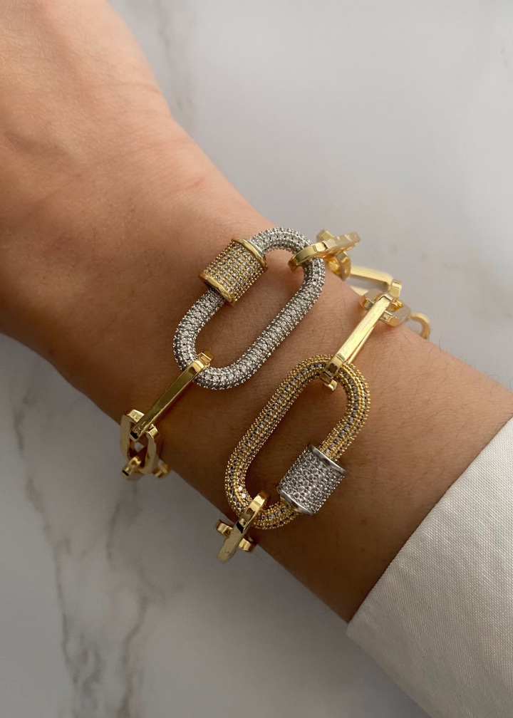Woman wearing a two gold paperclip chain bracelets with carabiners