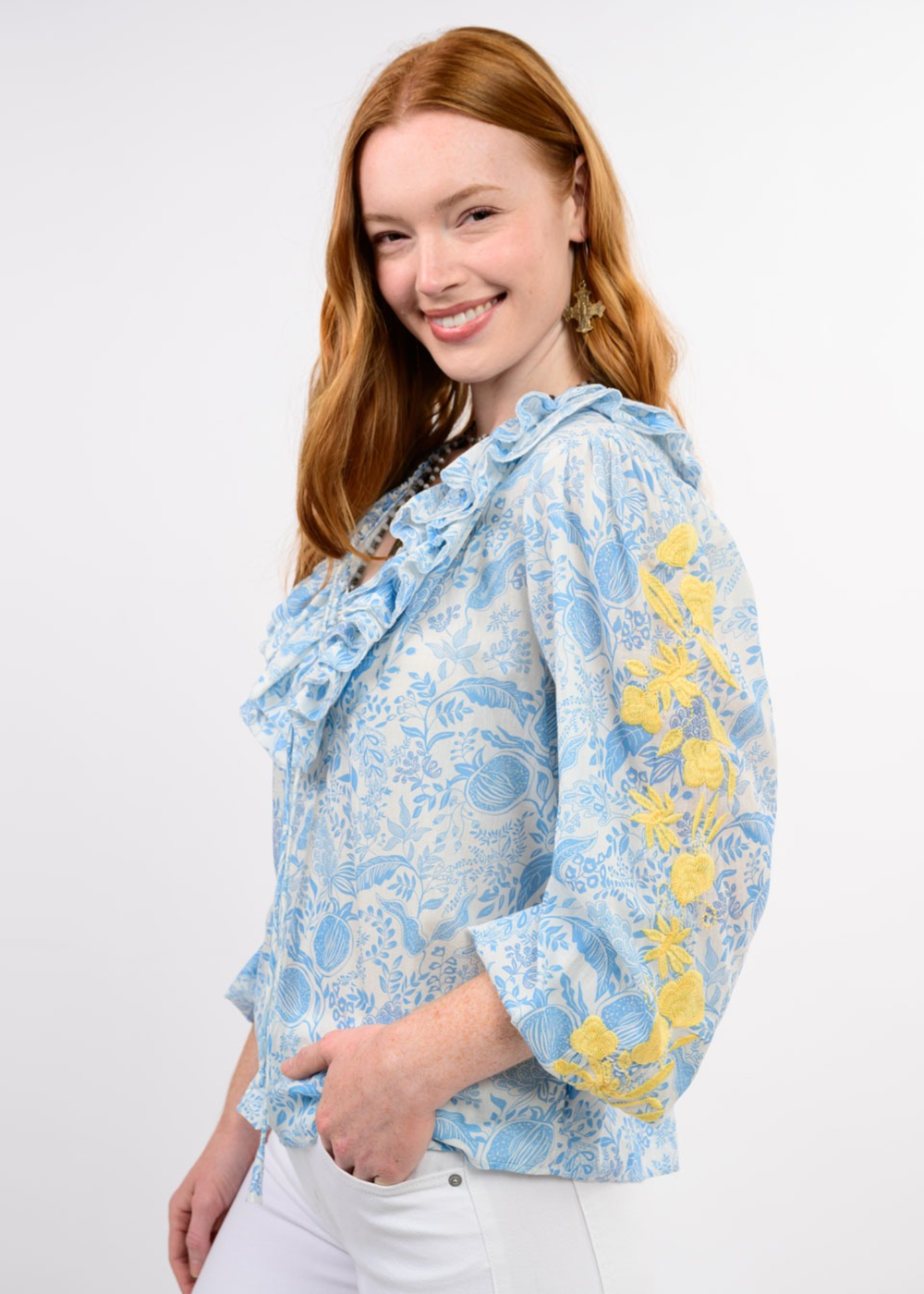 Woman wearing a blue floral top with yellow embroidery on the sleeves