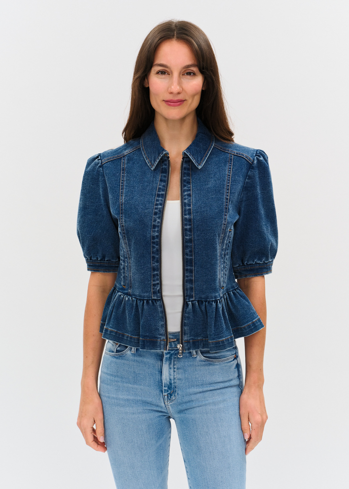 Woman wearing a dark denim jacket with puff sleeves and a peplum design over a white shirt and light wash jeans