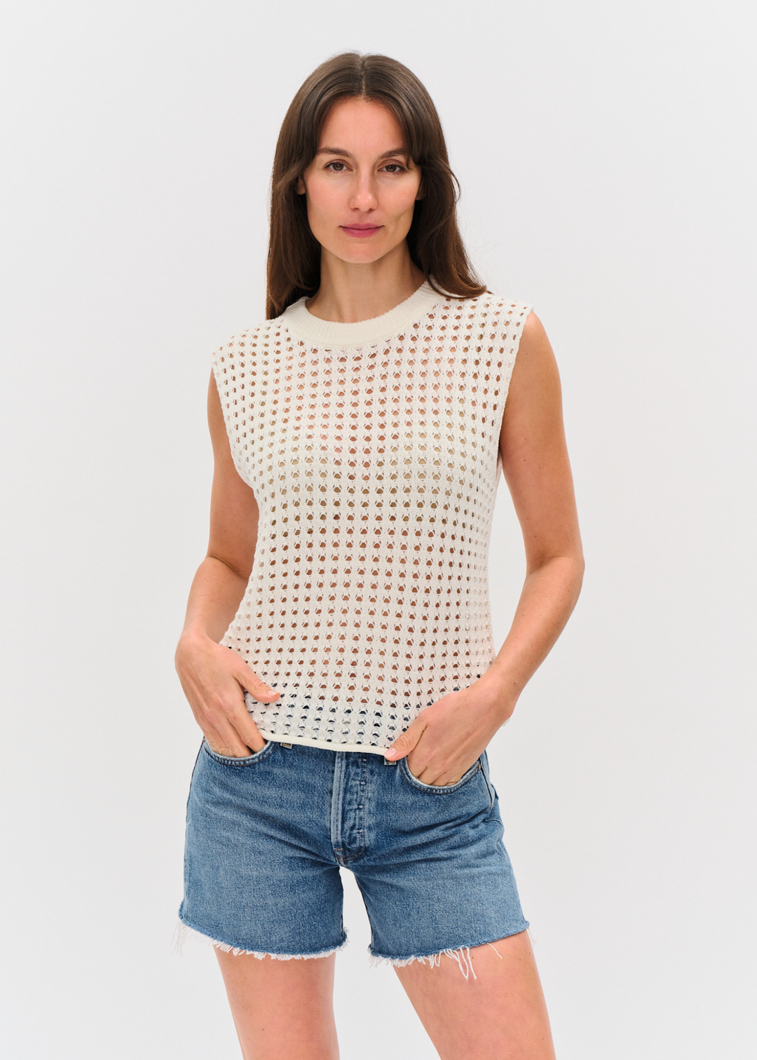 Woman wearing an ivory crochet tank top with denim shorts