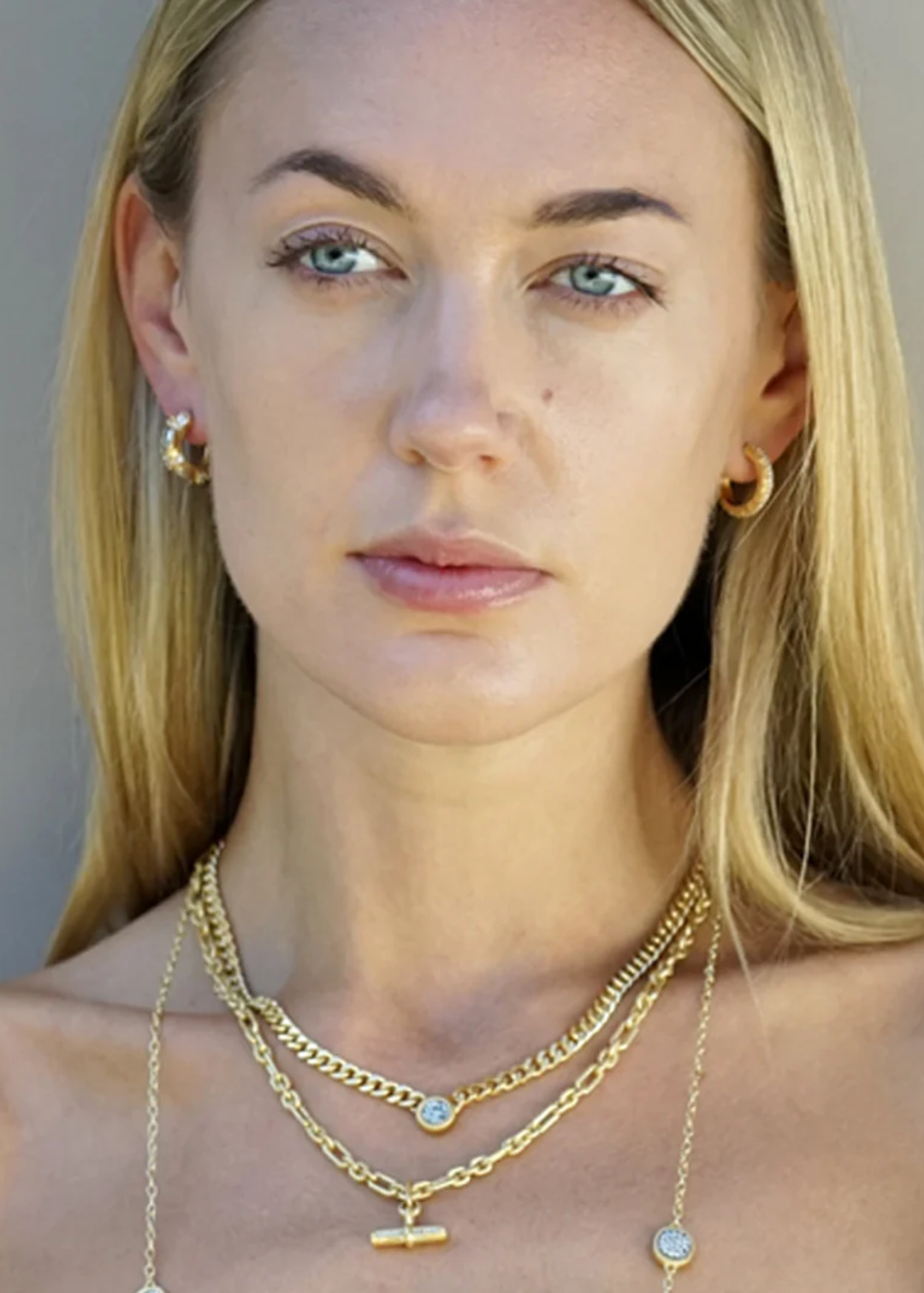 Woman wearing gold necklaces including a gold chain necklace with silver coins