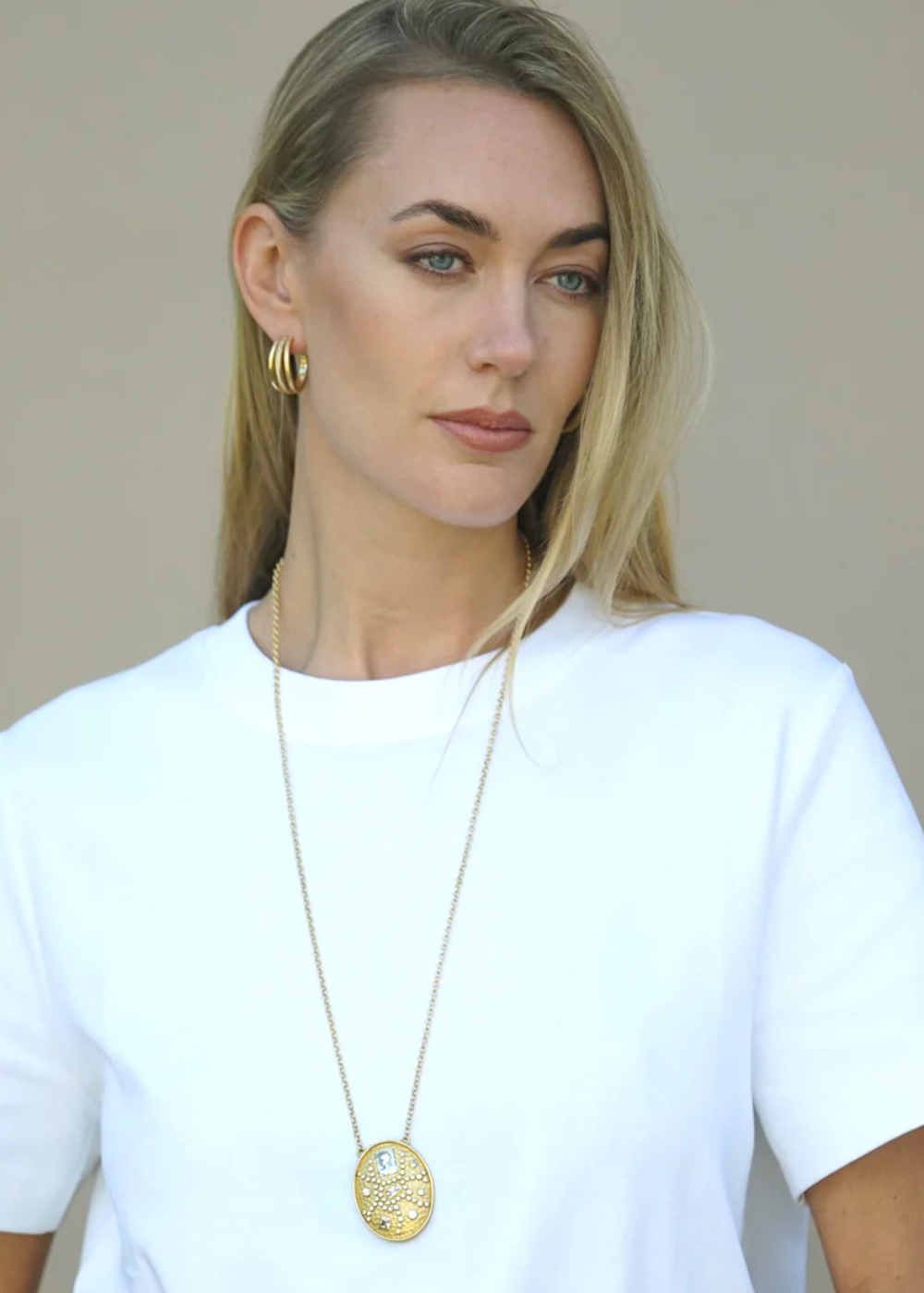 Woman wearing a gold pendant necklace with CZ and vintage silver accents