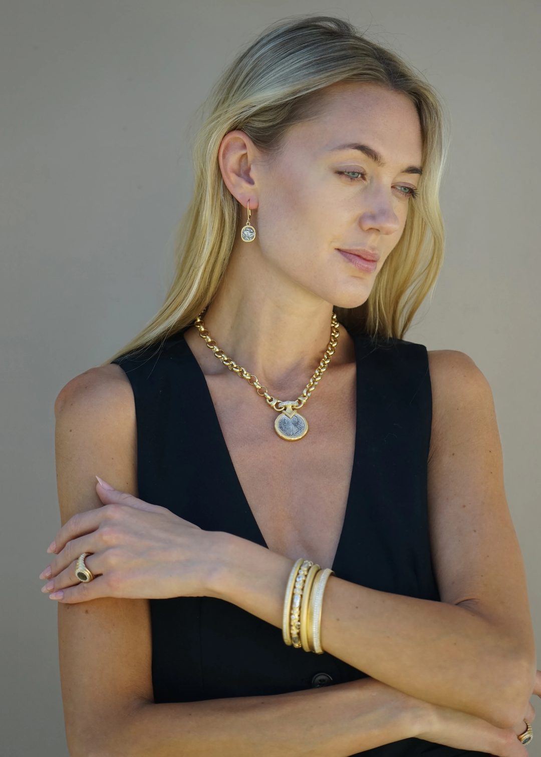 Woman wearing a gold chain necklace with a silver coin pendant