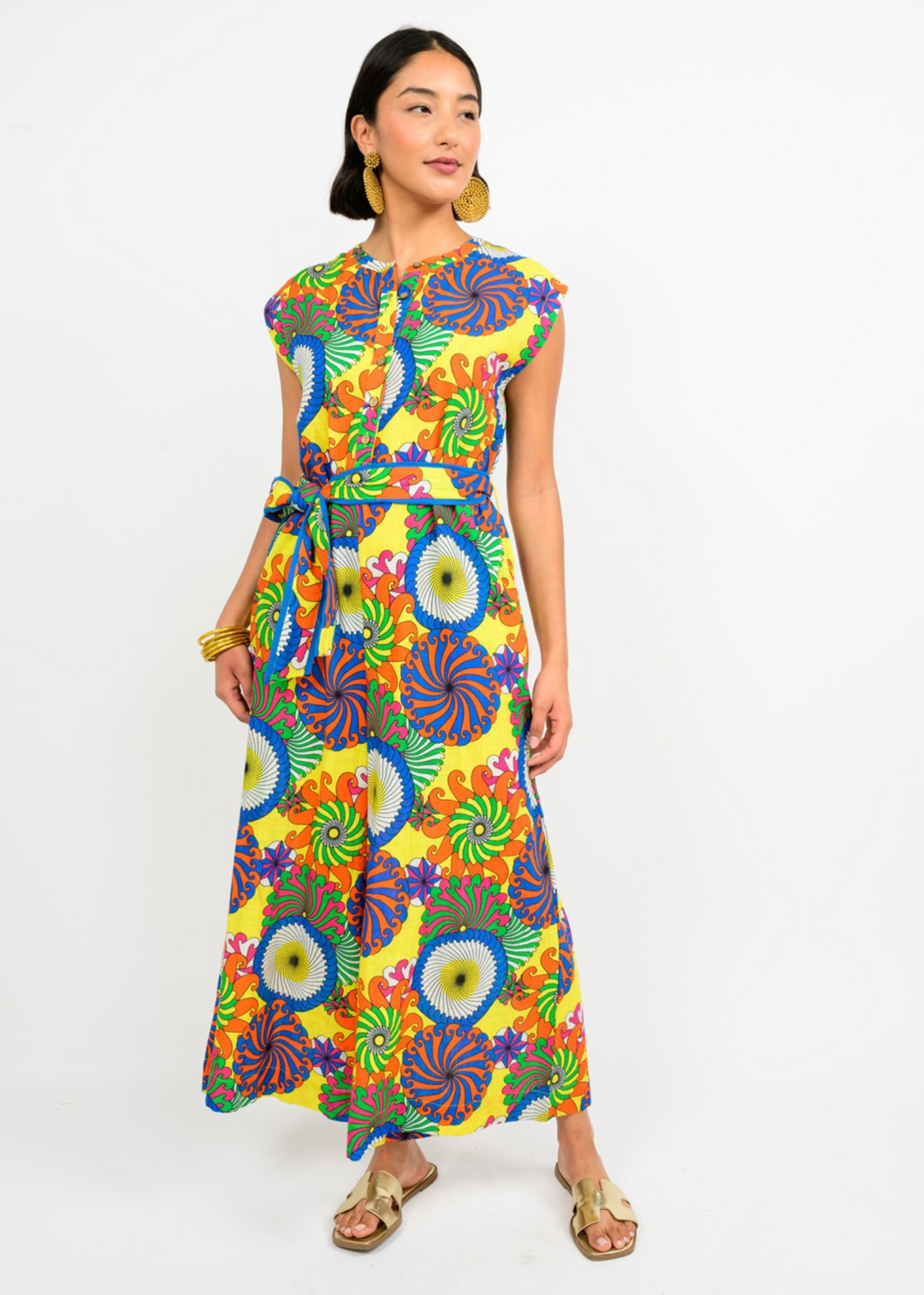 woman wearing wide leg, sleeveless jumpsuit in a bright abstract floral print with waist tie