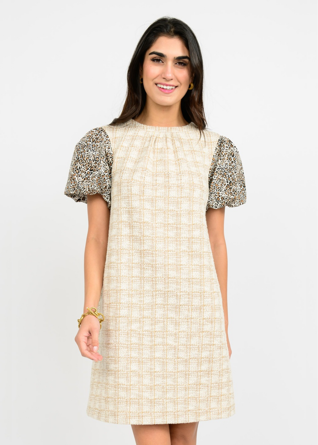 Woman wearing a tan and cream colored mini dress with leopard print puff sleeves in front of a white background