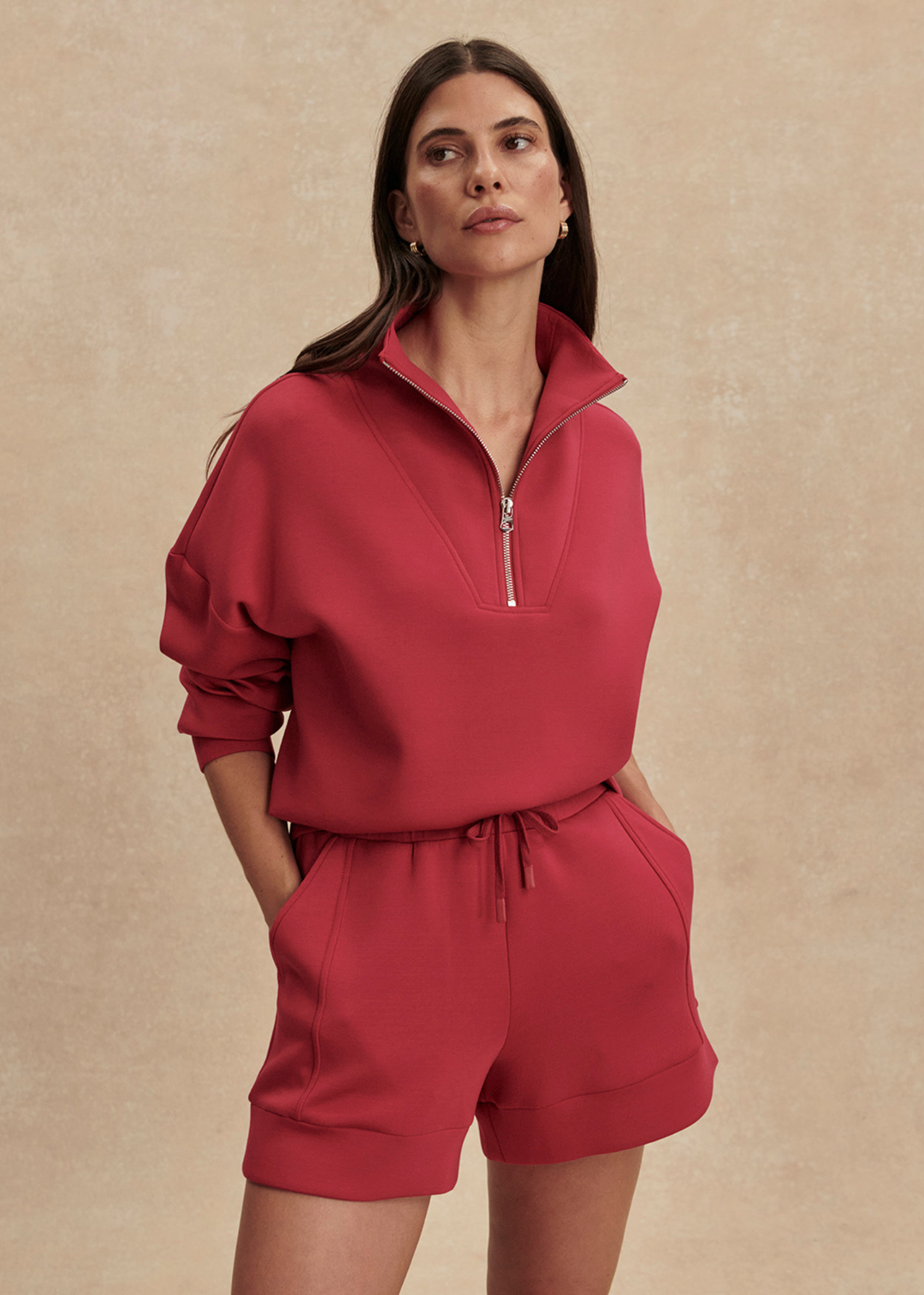 Woman wearing pink shorts and a matching sweatshirt