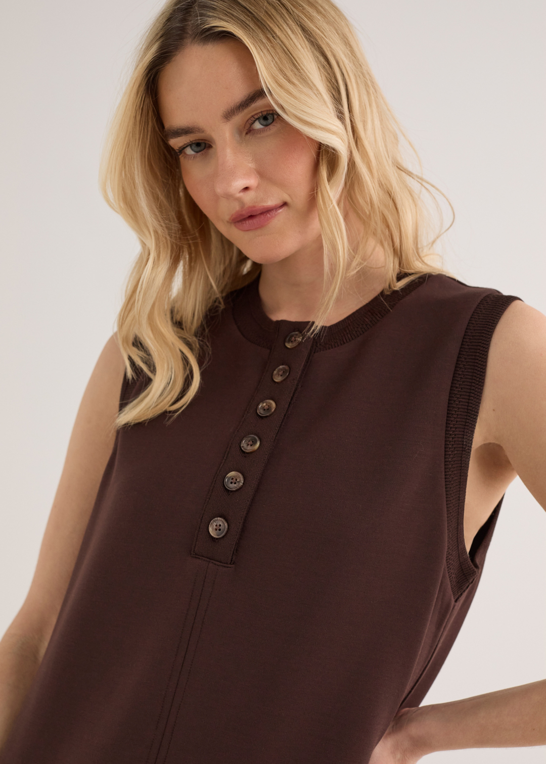 Close up of a woman wearing a brown sleeveless mini dress with yellow sandals