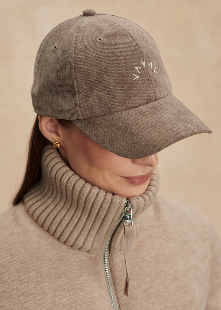 Woman with head turned wearing a brown hat with a "V" pattern