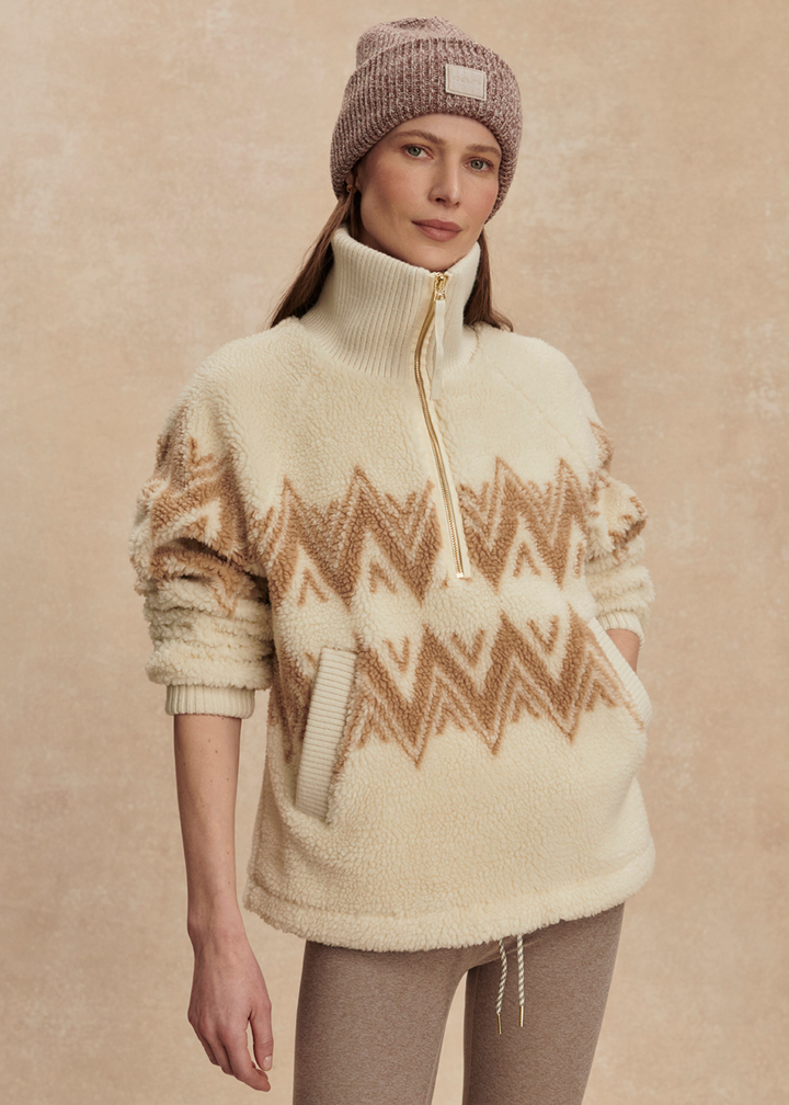 Woman wearing a cream and brown half zip sherpa with a brown beanie and leggings