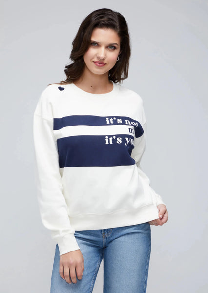 White sweatshirt with blue stripes and a a graphic reading "It's not me it's you" and a heart on the right shoulder