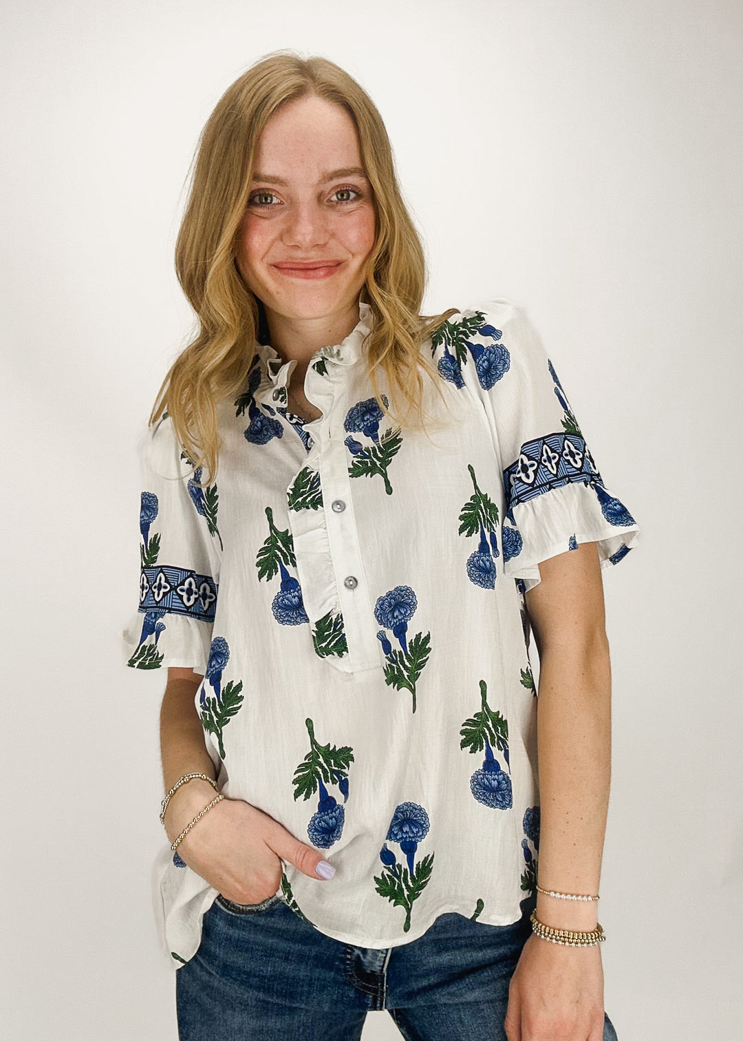 white short sleeve top with ruffle collar, short ruffle sleeves, and blue floral print