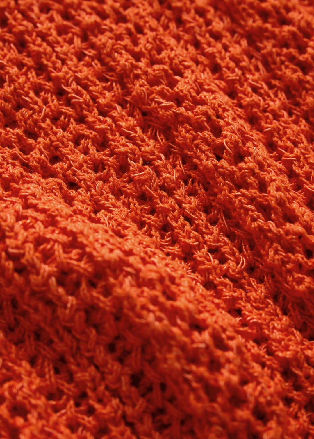 Close up of the fabric of an orange crochet top