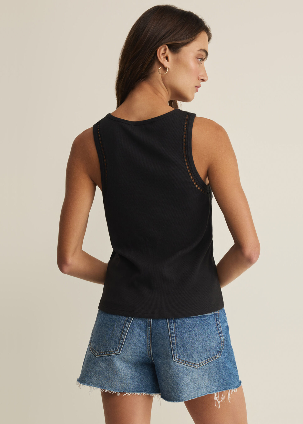 Woman turned around wearing a black tank with denim shorts