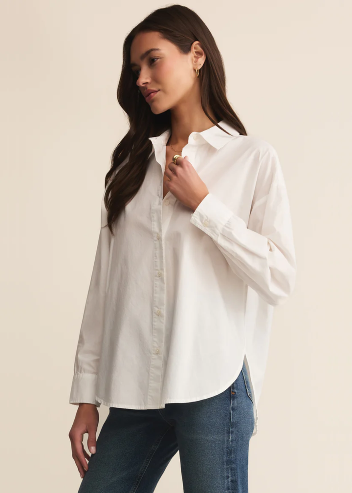 Woman wearing a white button down shirt with jeans and holding collar