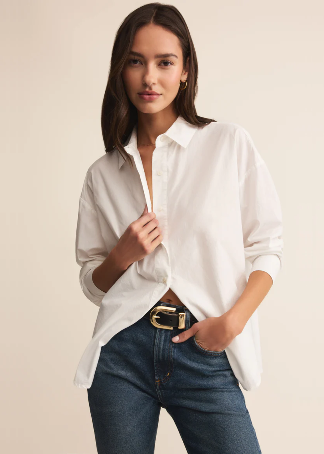 Woman wearing a white button down shirt with jeans and holding collar