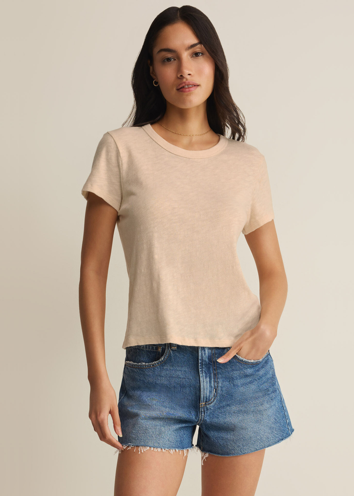 Woman wearing a tan t-shirt with denim shorts