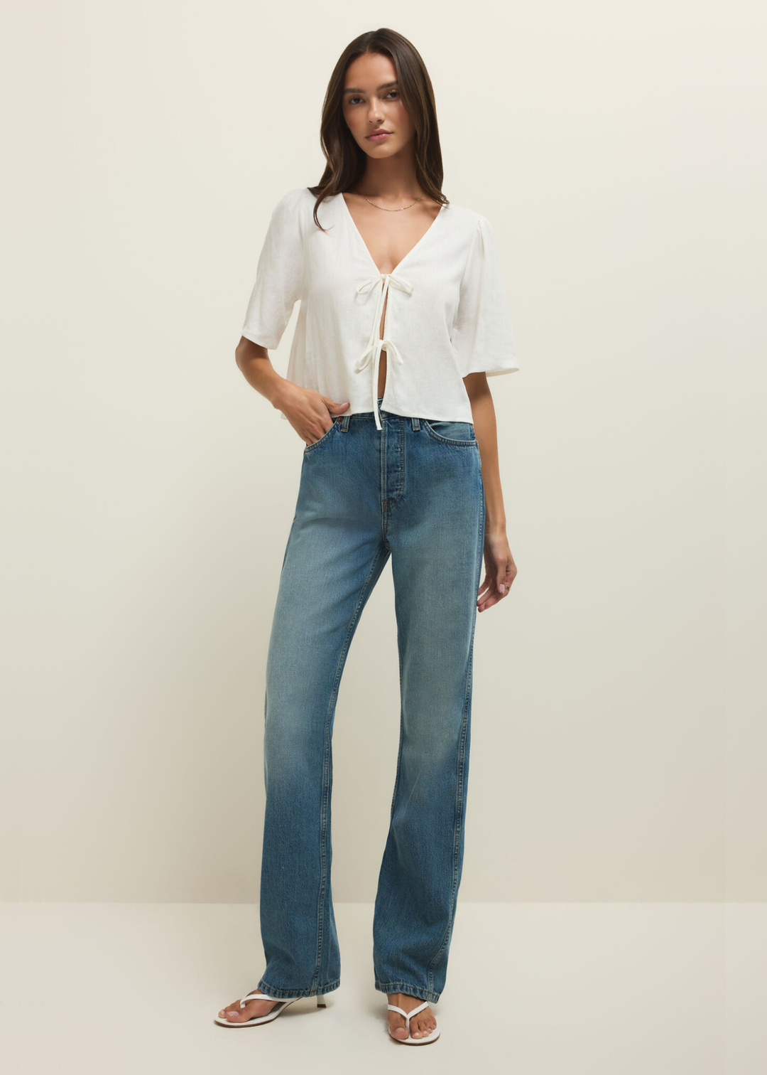 Woman wearing a short sleeve white linen tie front top with jeans