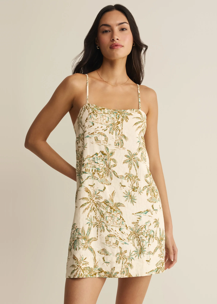 Woman wearing a cream mini dress with a tropical print
