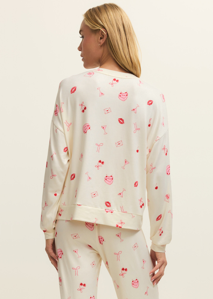 Woman turned around wearing a white pj set with a pink and red graphic pattern