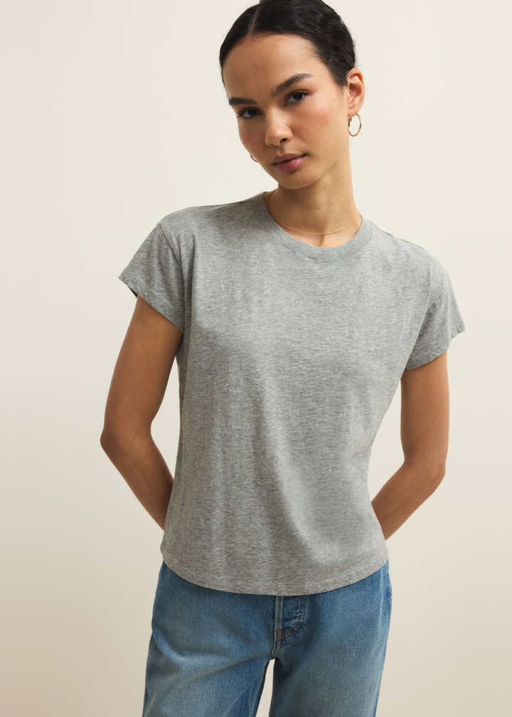 Woman wearing a grey short sleeve t-shirt and jeans against a grey background