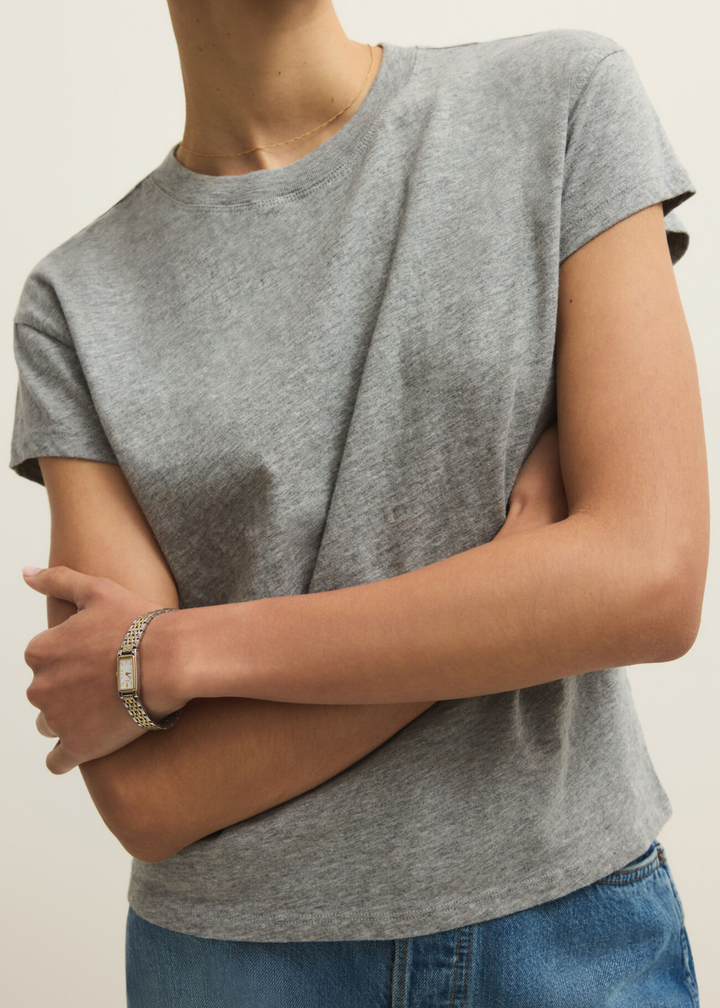 Close up of a woman wearing a grey short sleeve t-shirt and jeans against a grey background