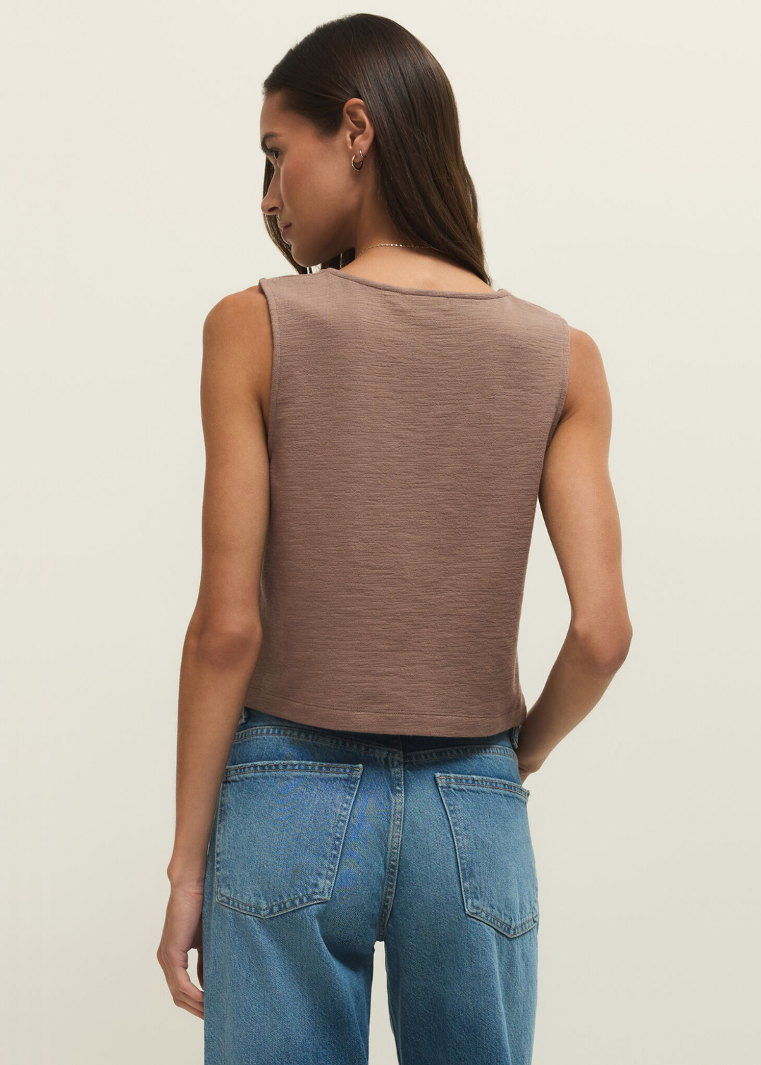 Woman turned around wearing a brown textured button down tank with jeans