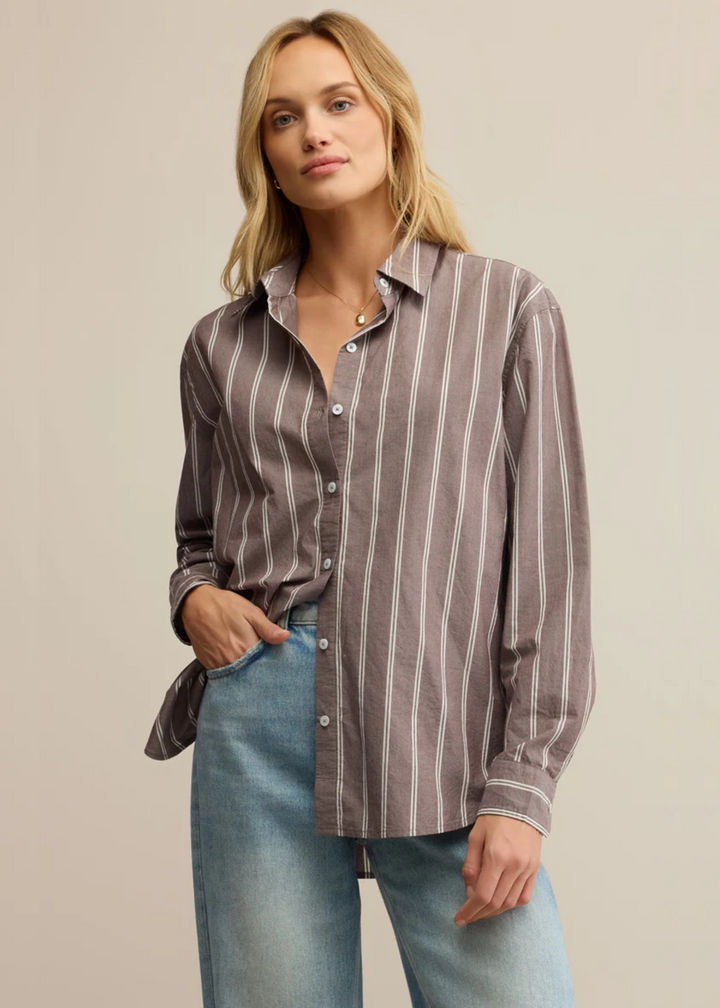 Woman wearing a brown striped poplin button down shirt with jeans in front of a grey background