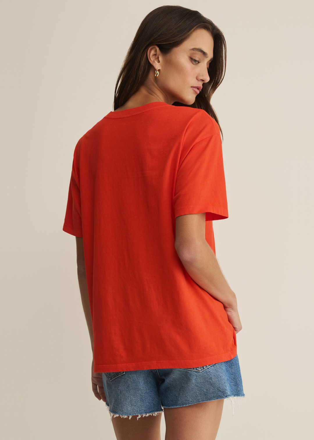 Woman wearing a red t-shirt with an "American Sweetheart" graphic and denim shorts