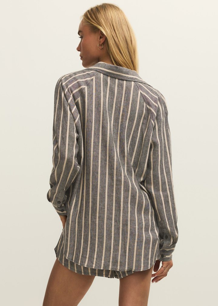 Woman turned around wearing a black button down with white stripes and matching shorts