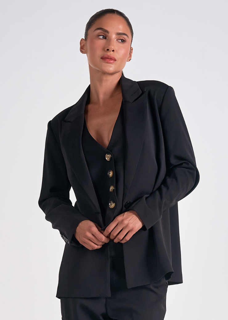 A black women's blazer with button detail, featuring a classic design from the Elan Truett collection.