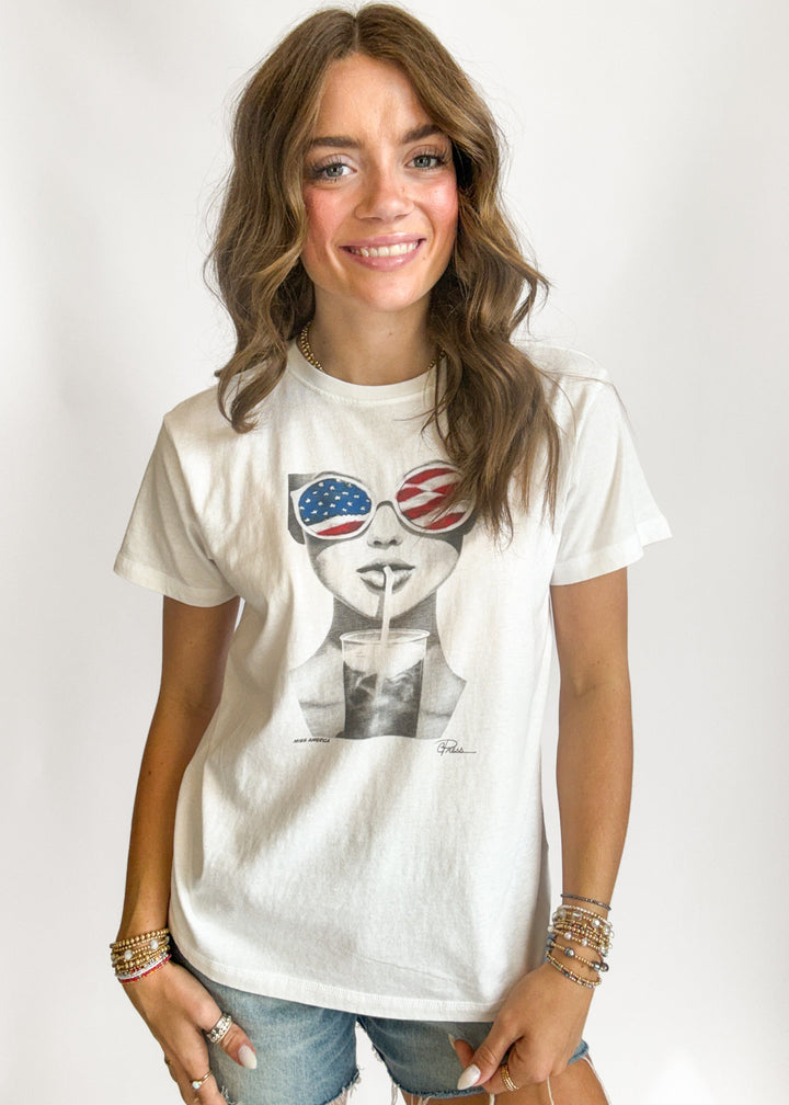 Woman wearing a white t-shirt with a graphic design on a plain background