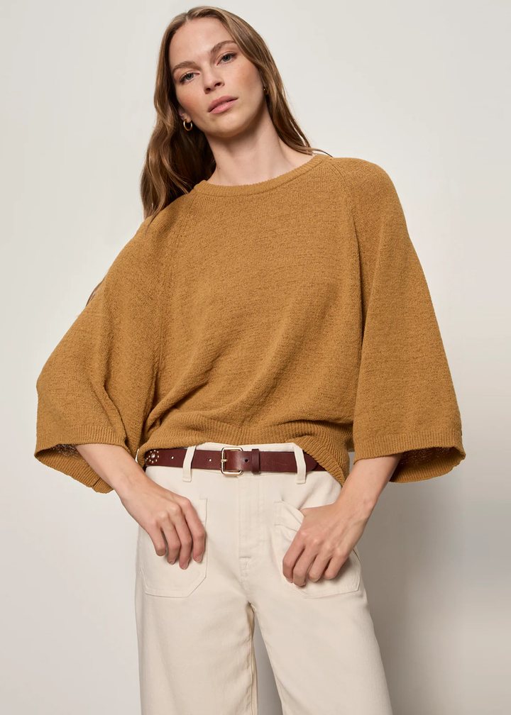 Woman wearing rust sweater with 3/4 length sleeves. 