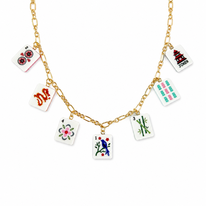 Gold necklace with playing card charm charms on a white background