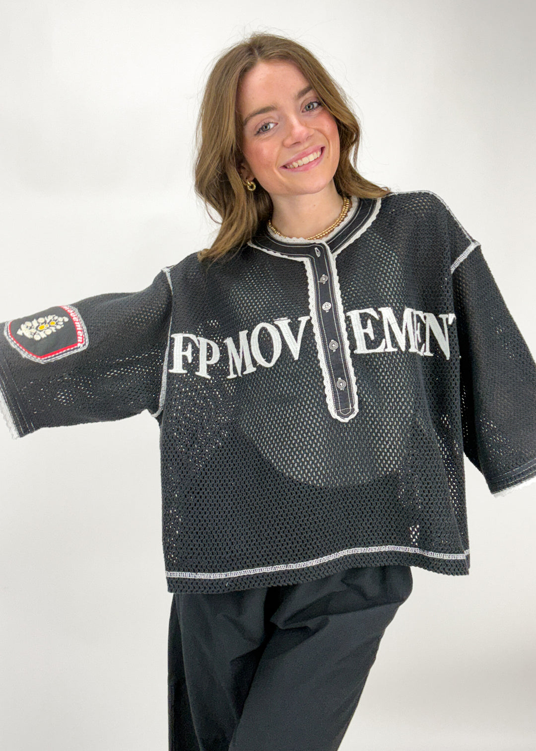 Person wearing a black mesh shirt with 'FP MOVEMENT' text on a white background