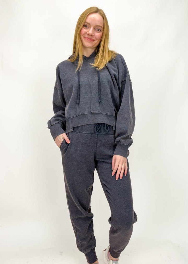Woman wearing a dark gray sweatshirt and pants on a white background